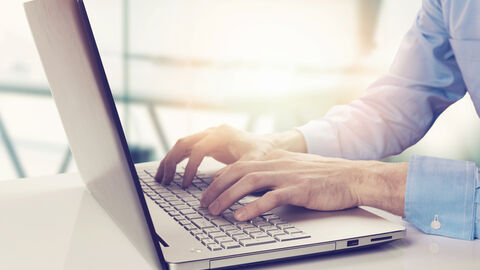 Mann tippt auf einem Notebook