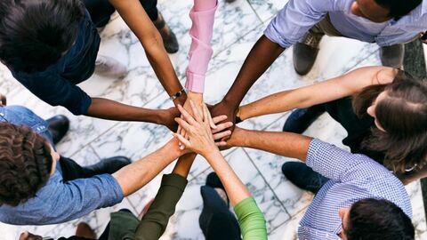 Gruppe legt die Hände zum Zeichen des Zusammenhalts übereinander.
