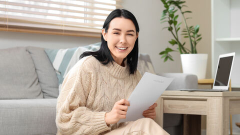 Glückliche junge Frau mit einem Rückerstattungsformular in ihren Händen